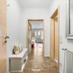 Flur mit Sitzbank, Spiegel und Blick in Schlafzimmer mit Fenster.