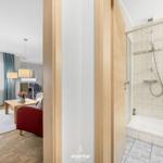 Badezimmer mit Dusche und Blick in Wohnbereich mit Sofa und Tisch.