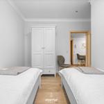 Zwei Betten, Kleiderschrank und Stuhl im Schlafzimmer. Durchgang zur Küche.