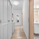 Flur mit Kleiderschrank und Blick in das Badezimmer mit Waschbecken und Spiegel.