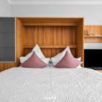 Schlafzimmer mit Bett, Holzregal und Fernseher.