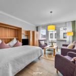 Schlafzimmer mit Bett und Wohnbereich mit Sitzgelegenheiten und Fenster.