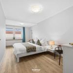 Schlafzimmer mit Bett, Nachttisch, Lampe und Fenster mit Blick.