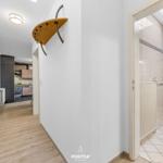 Flur mit Küchen- und Badezimmeransicht. Holzboden, Wandgarderobe und Dusche sichtbar.