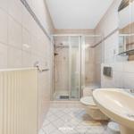 Bad mit Dusche, Waschbecken und Toilette. Fliesenwand und Boden.