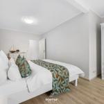 Schlafzimmer mit weißem Bett, Kleiderschrank und Holzboden