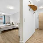 Schlafzimmer mit Bett und Fenster. Flur mit Tür und Wandhaken.