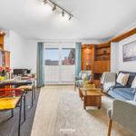 Wohn- und Essbereich mit Sofa, Tisch und Blick auf Balkon.