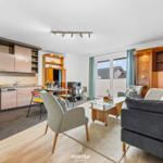 Wohn- und Küchenbereich mit Sitzgelegenheiten und Blick auf Balkon.