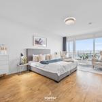 Schlafzimmer mit Balkon, Bett, Schrank und Sitzgelegenheiten.