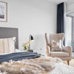 Schlafzimmer mit Bett, Sessel und Blick auf Balkon.