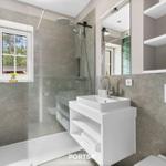 Badezimmer mit Dusche, Waschbecken und Fenster mit Blick nach draußen.