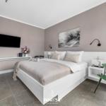 Schlafzimmer mit Bett, Fernseher und grüner Stuhl.