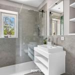 Badezimmer mit Dusche, Waschbecken und Fenster zum Garten