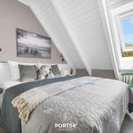 Schlafzimmer mit Dachschräge, Fenster und Bett mit Decke.