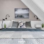Schlafzimmer mit Dachschräge, Bett mit Kissen und Wandbild.