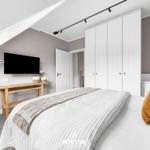 Schlafzimmer mit Dachschräge, Bett, Kleiderschrank und Fernseher an der Wand.