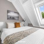 Schlafzimmer mit Dachfenster, Bett, Wandbild und Nachttisch.