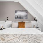 Schlafzimmer mit Dachschrägen, Bett, Kissen und Wandbild.