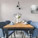 Esstisch mit blauen Stühlen und Blumendeko an der Wand