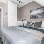 Schlafzimmer mit Bett, Kleiderschrank und Wandbild. Dachschrägen und neutrale Farben.