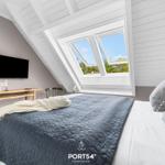 Schlafzimmer mit Dachfenster, Bett, Fernseher und Holztisch.