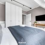 Schlafzimmer mit Bett, Kleiderschrank und Fernseher an der Wand.