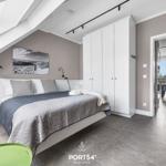 Schlafzimmer mit Dachschrägen, Bett, Kleiderschrank und Blick in Wohnbereich.