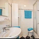 Badezimmer mit Dusche, Waschbecken und blauen Handtüchern.