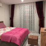 Schlafzimmer mit Bett, Vorhängen und Schreibtisch.