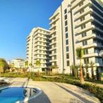 Modernes Apartmenthaus mit Pool und Palmenanlage im Freien.