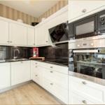 Küche mit weißen Schränken, schwarzer Arbeitsplatte und integriertem Herd.