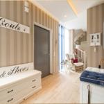 Eingangsbereich mit Garderobe, Sitzbank und Stauraum. Hintergrund zeigt Wohnbereich mit Sessel.