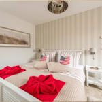 Schlafzimmer mit weißem Bett, gestreifter Wand und roten Handtüchern.