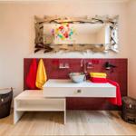 Badezimmer mit rotem Mosaik, weißem Waschtisch und Spiegel mit Glasdekoration.