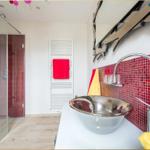 Badezimmer mit Glasdusche, rotem Mosaik und Keramikwaschbecken.