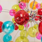 Farbige Glasbälle hängen an Metallstäben an einer Deckenleuchte.