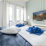 Schlafzimmer mit Bett, TV und Fenstern.