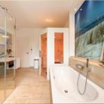 Badezimmer mit Whirlpool, Sauna und Duschbereich. Wandbild mit Segelboot.