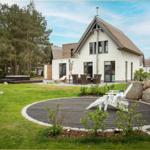 Moderne Villa mit Garten, Terrasse und Whirlpool. Weiße Holzterrasse mit Liegestühlen.