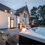 Modernes Haus mit Whirlpool, Terrasse und Garten bei Dämmerung.