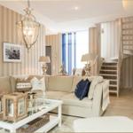 Wohnzimmer mit Sofa, Tisch und Treppenaufgang. Wandtapete und Bilder sichtbar.