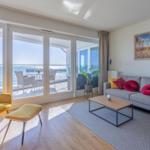 Wohnzimmer mit Blick aufs Meer, Sofa, Sessel und Terrasse.