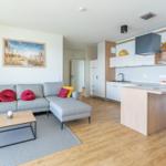 Wohnbereich mit Sofa, Couchtisch und offener Küche mit Kücheninsel.