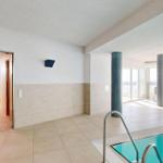 Innenpool mit Außenterrasse und Liegestühlen. Tür führt in Dampfbad.