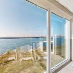 Großes Fenster mit Meerblick auf einen Steg und Wasser.