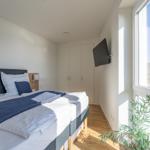 Schlafzimmer mit Blick aufs Meer, Bett, Kleiderschrank und Wand-TV.