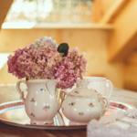 Auf einem Holztisch steht eine Teeservice mit Blumenstrauß.