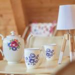 Tisch mit Teekanne, Tassen und einer Lampe in einem Holzhaus.