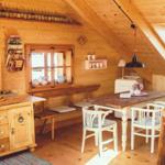 Küche mit Essbereich, Holzwände und -decke, Fenster und Schränke.